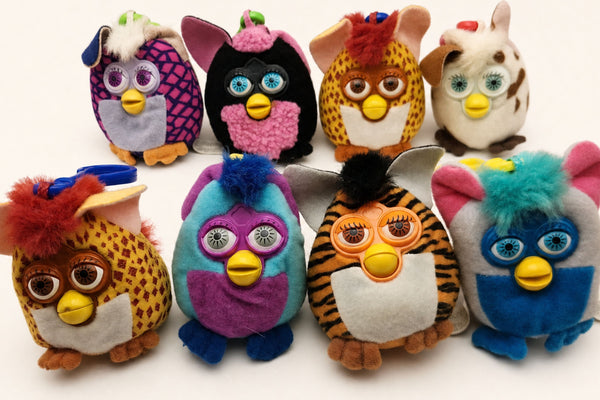 Eight McDonald's Furby plush clip-on toys in assorted colours and patterns grouped on a white background