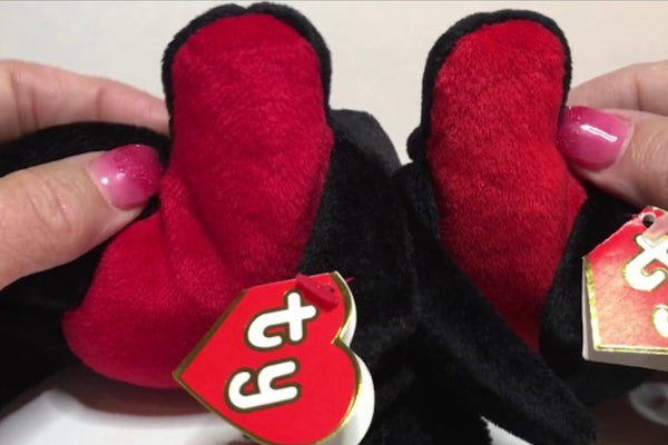 Two matching black and red Beanie Babies held side by side for comparison, ty swing tags visible.