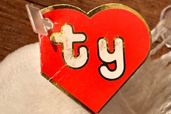 Close-up of a red heart-shaped Ty swing tag attached to a white Beanie Baby