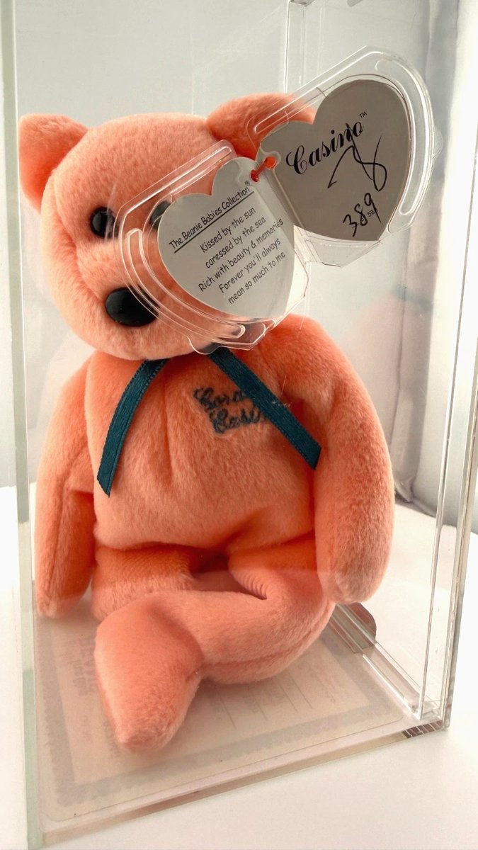 Peach Coral Casino bear in a display case, its signed hang tag numbered 389