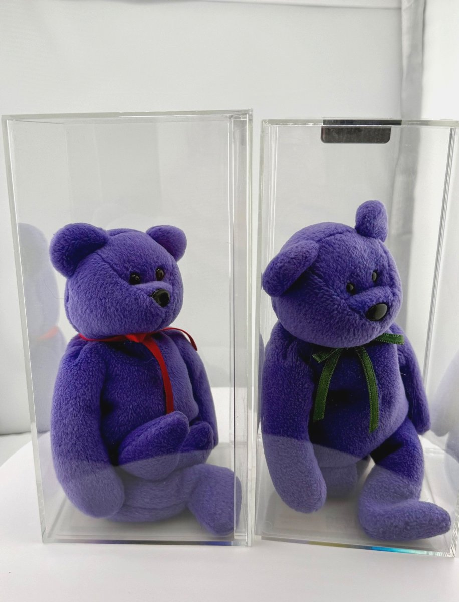 A pair of violet Employee Teddy bears, one with a red ribbon and one with a green ribbon, in display cases